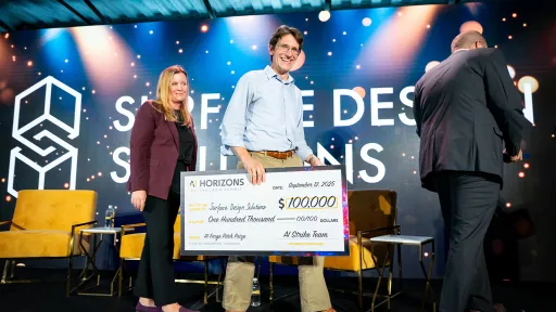 Tevis holding large novelty check on stage during an awards event.