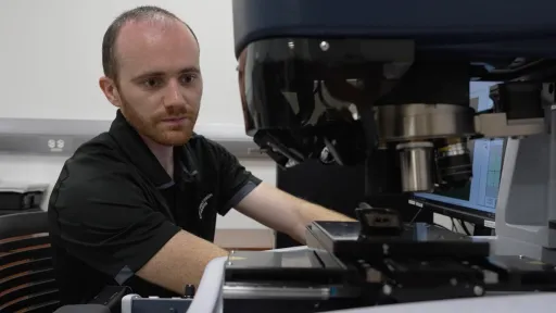 Luke intently operating a large scientific microscope.